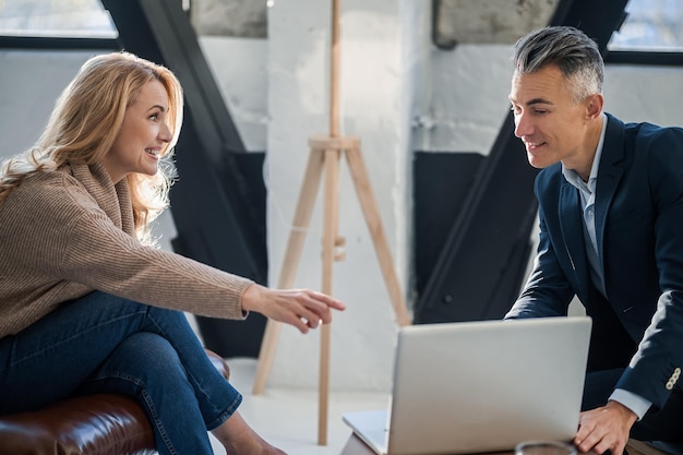 Femme blonde et un homme d'âge moyen regardant quelque chose sur un ordinateur portable et discutant