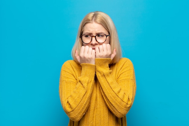 Femme blonde à l'inquiétude, anxieuse, stressée et peur, se ronger les ongles et à la recherche de l'espace de copie latérale