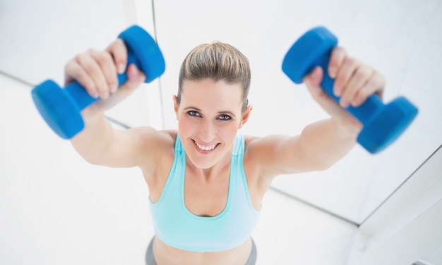 Femme blonde joyeuse, exercice avec des haltères