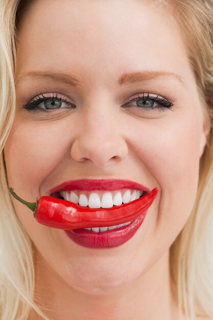 Photo femme blonde joyeuse plaçant un piment entre ses dents