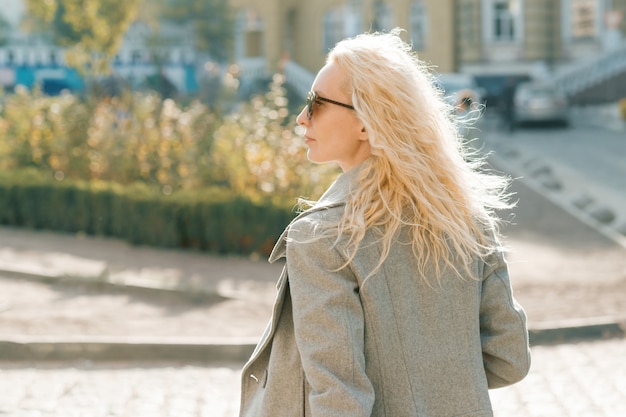 femme blonde avec des lunettes de soleil aux longs cheveux bouclés