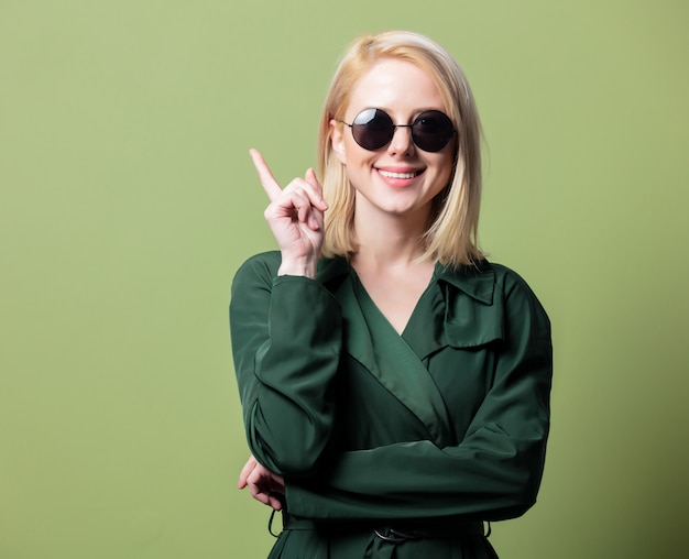 Femme blonde en manteau et lunettes de soleil rondes