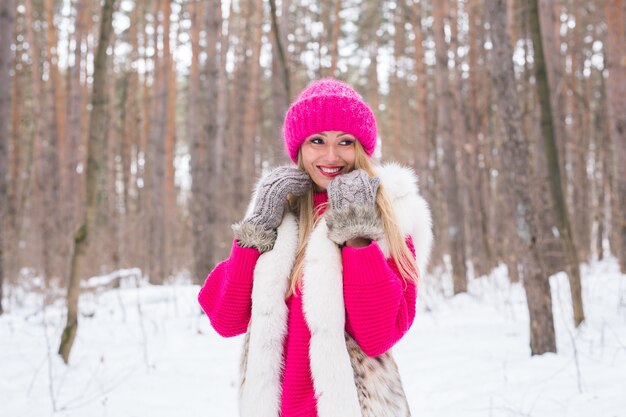 Femme blonde marchant dans un chapeau rose et des pulls en bois d'hiver