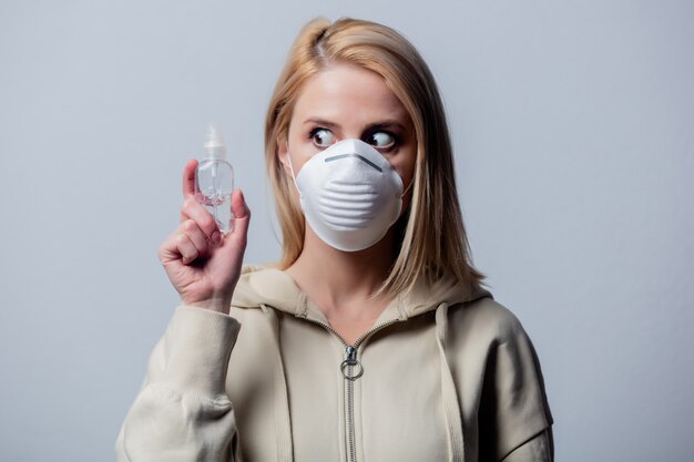 Femme blonde en masque de protection avec gel désinfectant