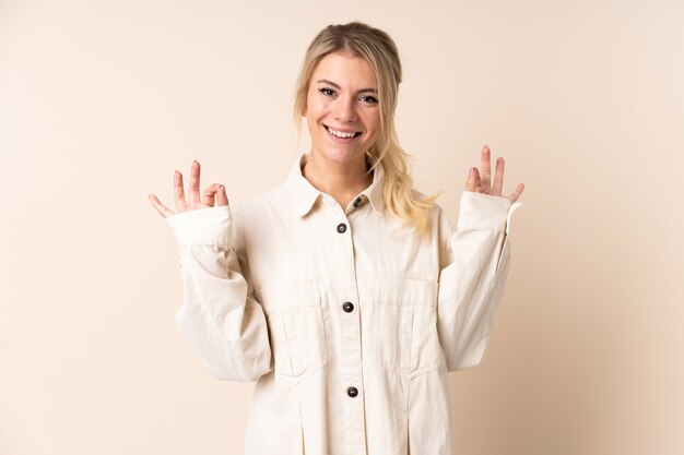 Femme blonde sur mur isolé montrant signe ok avec deux mains