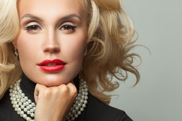 Une femme blonde parfaite avec un collier de perles.