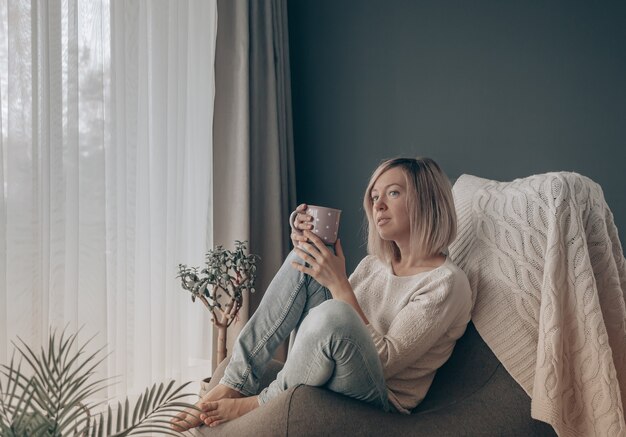 Femme blonde pensant tout en prenant un café