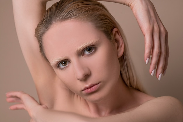 Une femme blonde. Une photo de taille d'une jeune femme blonde avec ses mains près du visage