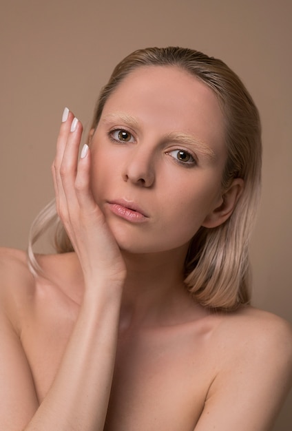 Une femme blonde. Une photo de taille d'une jeune femme blonde avec ses mains près du visage