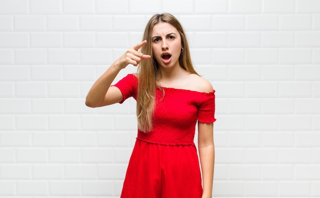 Femme blonde pointant avec une expression agressive en colère