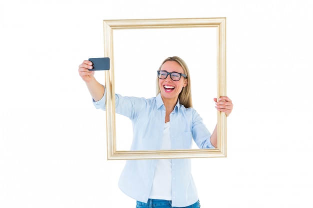 Femme blonde prenant un selfie à travers un cadre