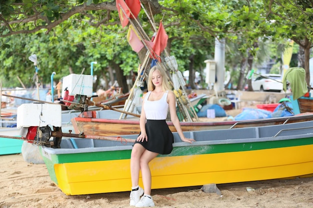 Femme blonde regardant détourner le regard et le soleil brille doucement sur son visage alors qu'il était assis sur la plage