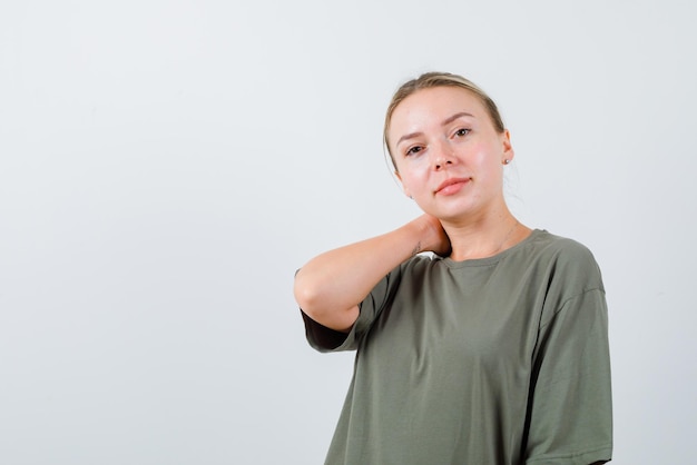 La femme blonde regarde la caméra en tenant sa main sur le cou sur fond blanc