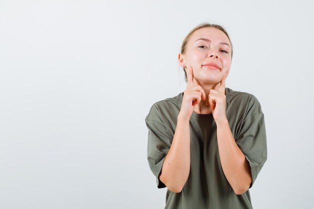 La femme blonde regarde la caméra en tenant ses index sur les chèques sur fond blanc