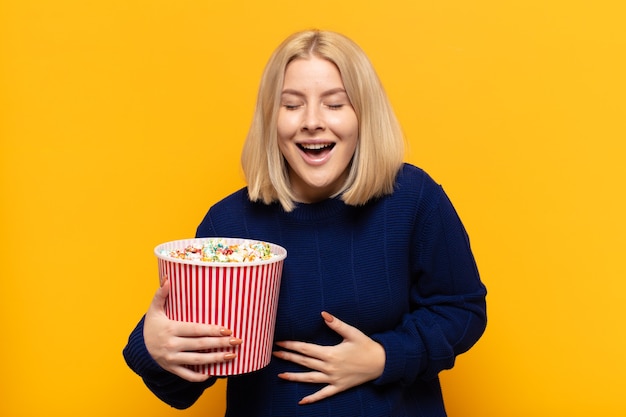 Femme blonde riant aux éclats d'une blague hilarante, se sentant heureuse et joyeuse