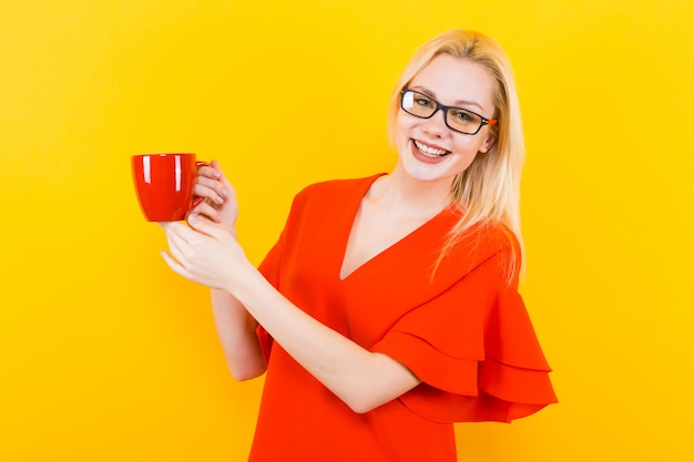 Femme blonde en robe rouge avec une tasse