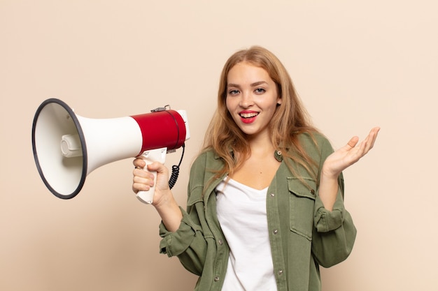 Femme blonde se sentant heureuse, surprise et joyeuse, souriante avec une attitude positive, réalisant une solution ou une idée