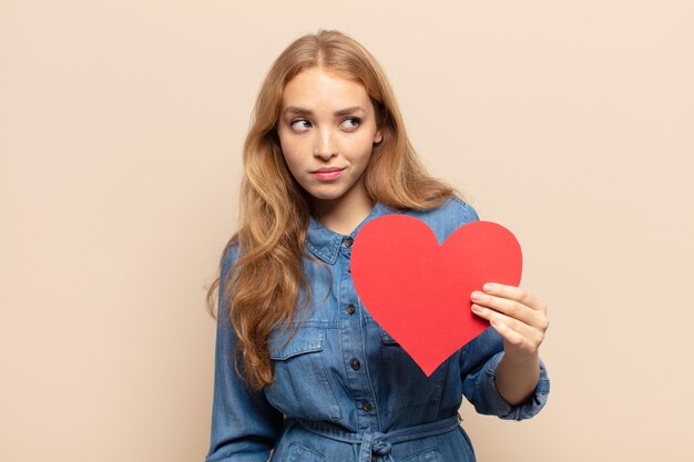 Femme blonde se sentant triste, bouleversée ou en colère et regardant sur le côté avec une attitude négative, fronçant les sourcils en désaccord