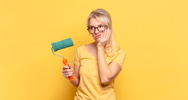 Femme blonde se sentir ennuyé, frustré et somnolent après une tâche fatigante, terne et fastidieuse, tenant le visage avec la main