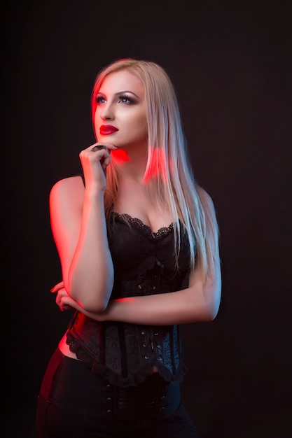 Femme blonde séduisante dans un corset avec la lumière rouge et bleue