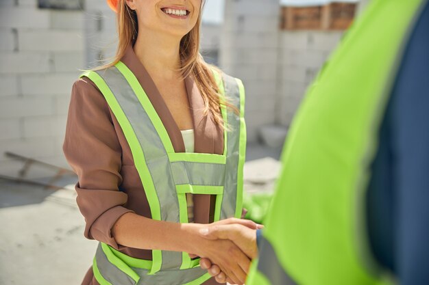 une femme blonde serrant la main de son collègue masculin sur un chantier de construction