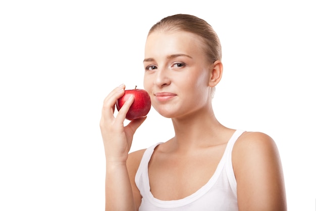 Femme blonde souriante mangeant une pomme rouge sur blanc