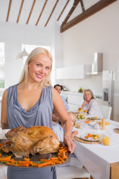 Femme blonde souriante, montrant la dinde rôtie