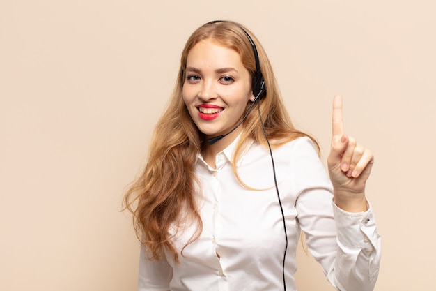 Femme blonde souriante et à la sympathique, montrant le numéro un ou d'abord avec la main en avant, compte à rebours