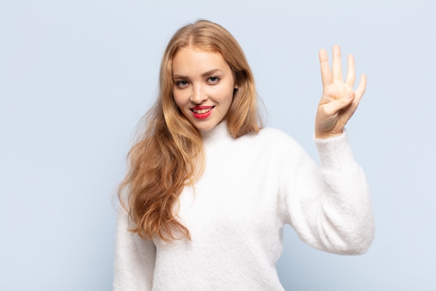 Femme blonde souriante et à la sympathique, montrant le numéro quatre ou quatrième avec la main en avant, compte à rebours