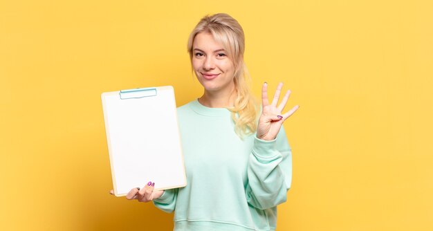 Femme blonde souriante et à la sympathique, montrant le numéro quatre ou quatrième avec la main en avant, compte à rebours