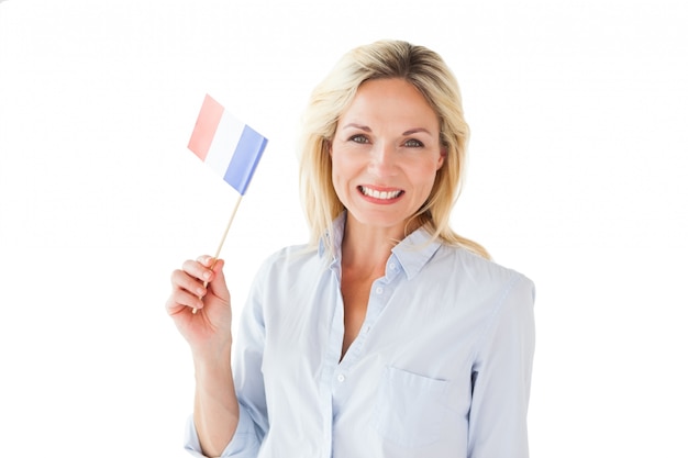 Femme blonde souriante tenant le drapeau français