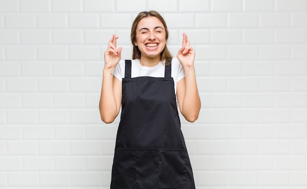 Photo femme blonde souriante et traversant anxieusement les deux doigts, se sentant inquiète et souhaitant ou espérant bonne chance