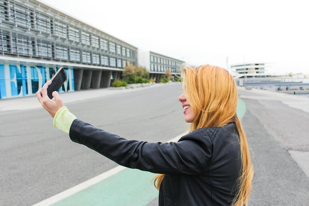 Photo femme blonde avec un téléphone prenant un selfie