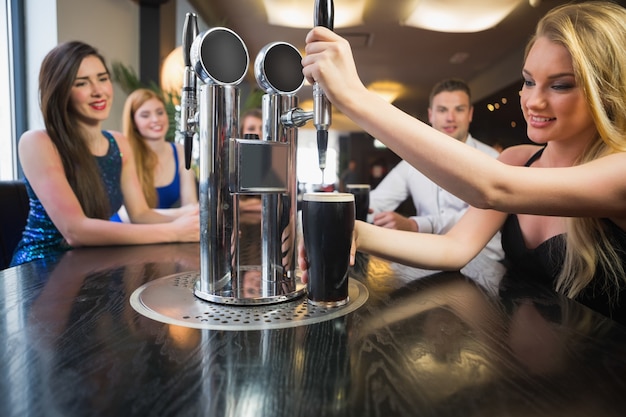 Femme blonde tirant une pinte de stout