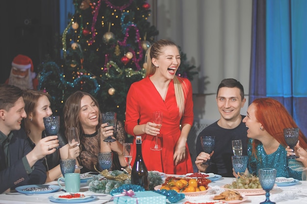 Femme blonde en toasts rouges à des amis à table à Noël et au nouvel an.