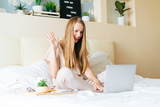 Femme blonde travaillant à la maison avec un ordinateur portable