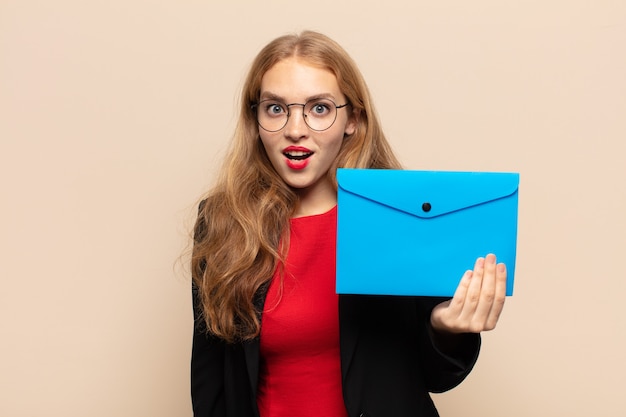 Femme blonde à la très choquée ou surprise, regardant la bouche ouverte en disant wow