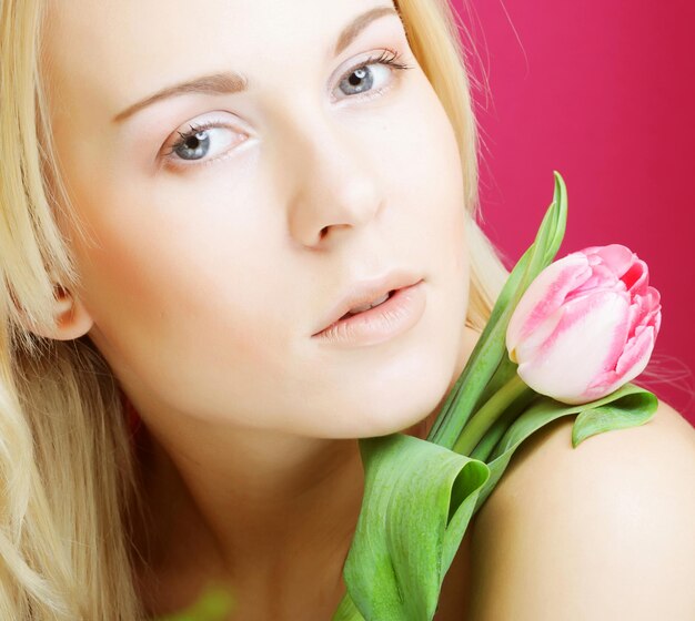 Photo femme blonde avec une tulipe rose