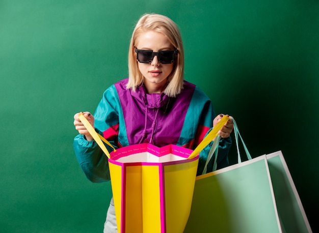 Femme blonde en veste de style des années 90 avec des sacs à provisions