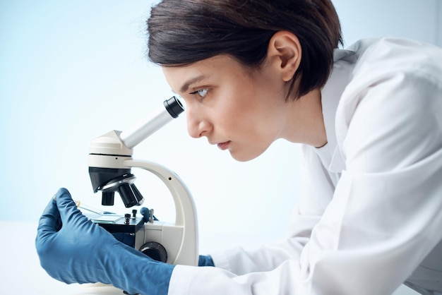 Femme en blouse blanche regarde à travers l'expérience des professionnels de la science de laboratoire de microscope