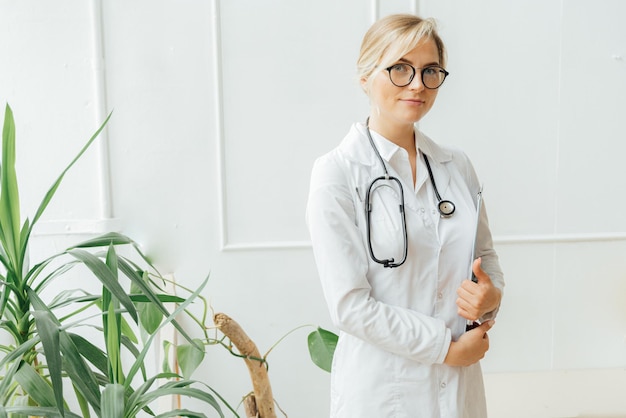 Une femme en blouse blanche se tient devant une plante