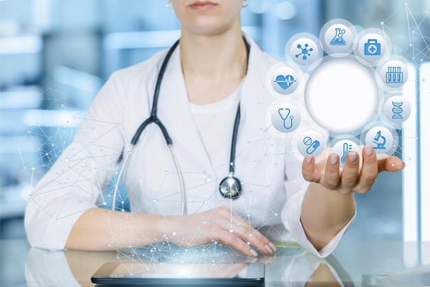Une femme en blouse blanche tient une tablette avec des icônes de dispositifs médicaux.