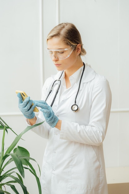 Une femme en blouse de laboratoire et lunettes de protection regarde une éponge jaune.