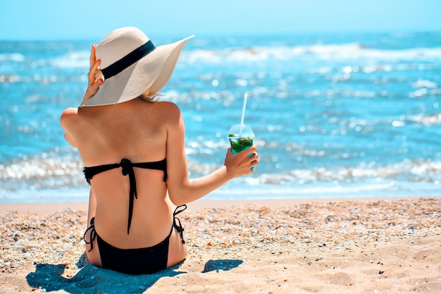 Femme avec boisson au bord de la mer