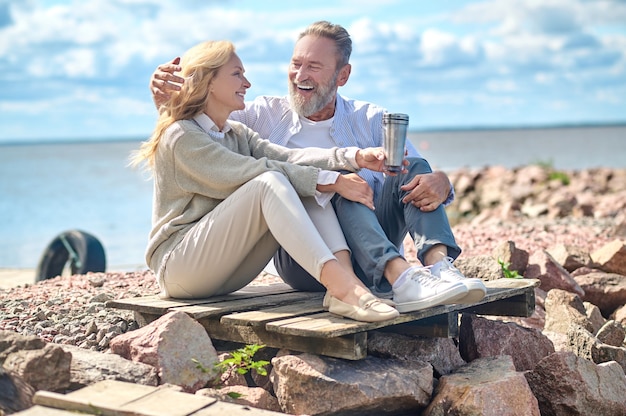 Photo femme avec boisson et homme riant assis à l'extérieur