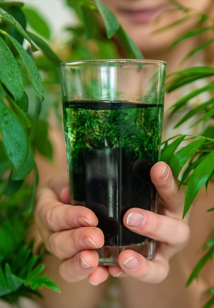 Une femme boit de la chlorophylle liquide Mise au point sélective