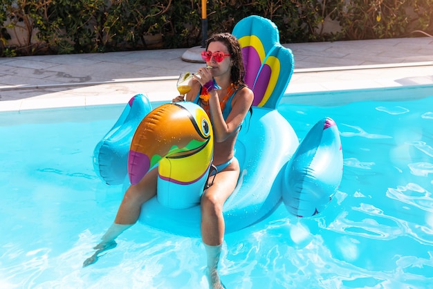 Femme boit un cocktail dans une piscine