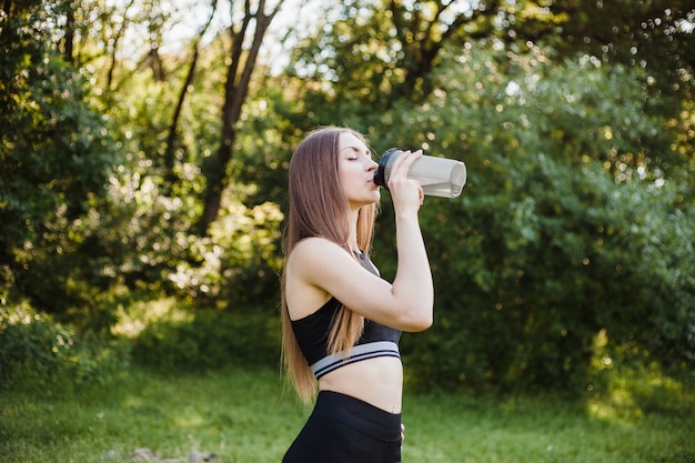 Femme boit un cocktail sportif dans le parc