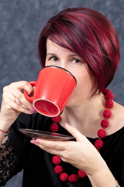 Une femme boit dans une tasse rouge