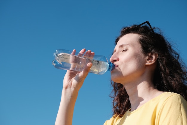 La femme boit de l'eau d'une bouteille par temps chaud